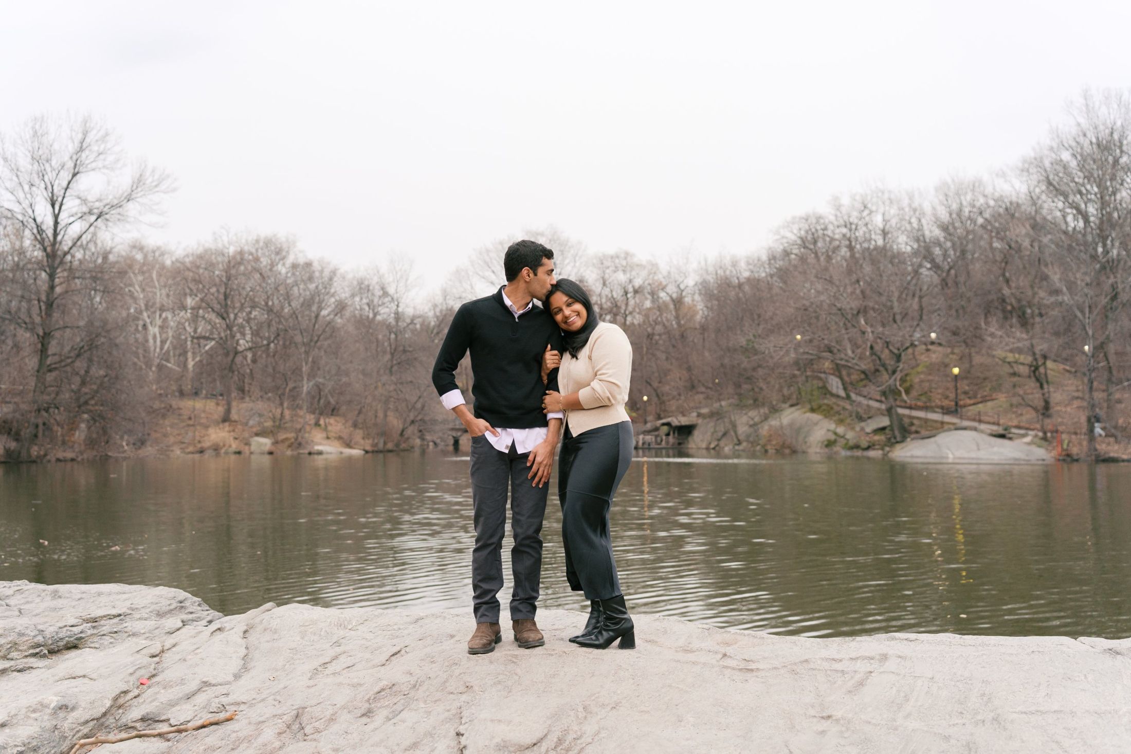 Manu and Nikhil standing by the lake, embracing