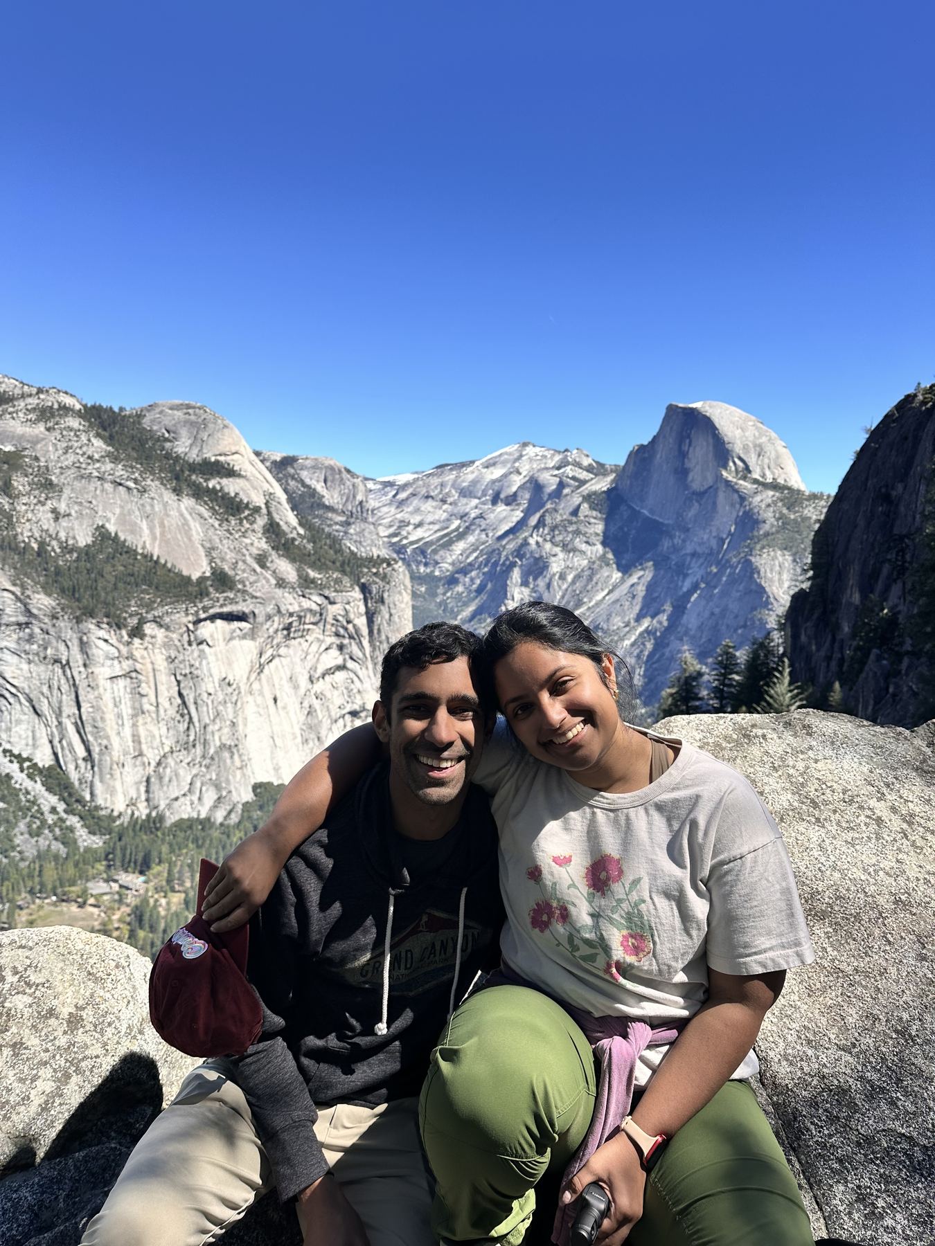 Manu and Nikhil sitting on a rock in Yosemite with Half Dome behind them